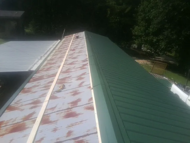 Old rusted panels beside newly installed green metal roofing — Wind Damage Roof Repair by Roofing Brothers in White Hall