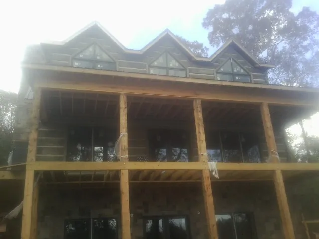 Dormers and porch framing on a large log home under construction — Roof Coating work by our crew in White Hall