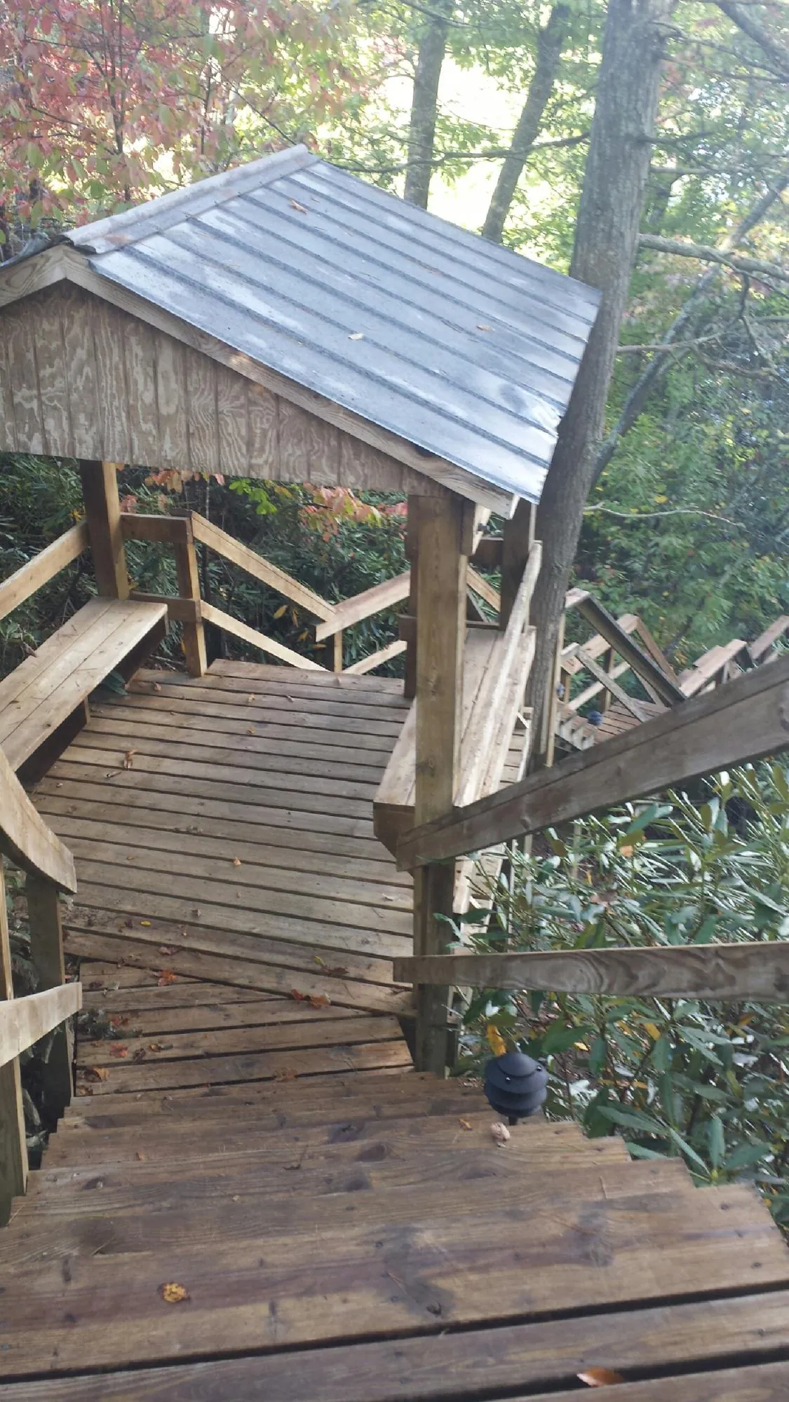 Metal roofed shelter over wooden steps on a wooded walkway — Skylight Repair & Installation work by our crew in White Hall