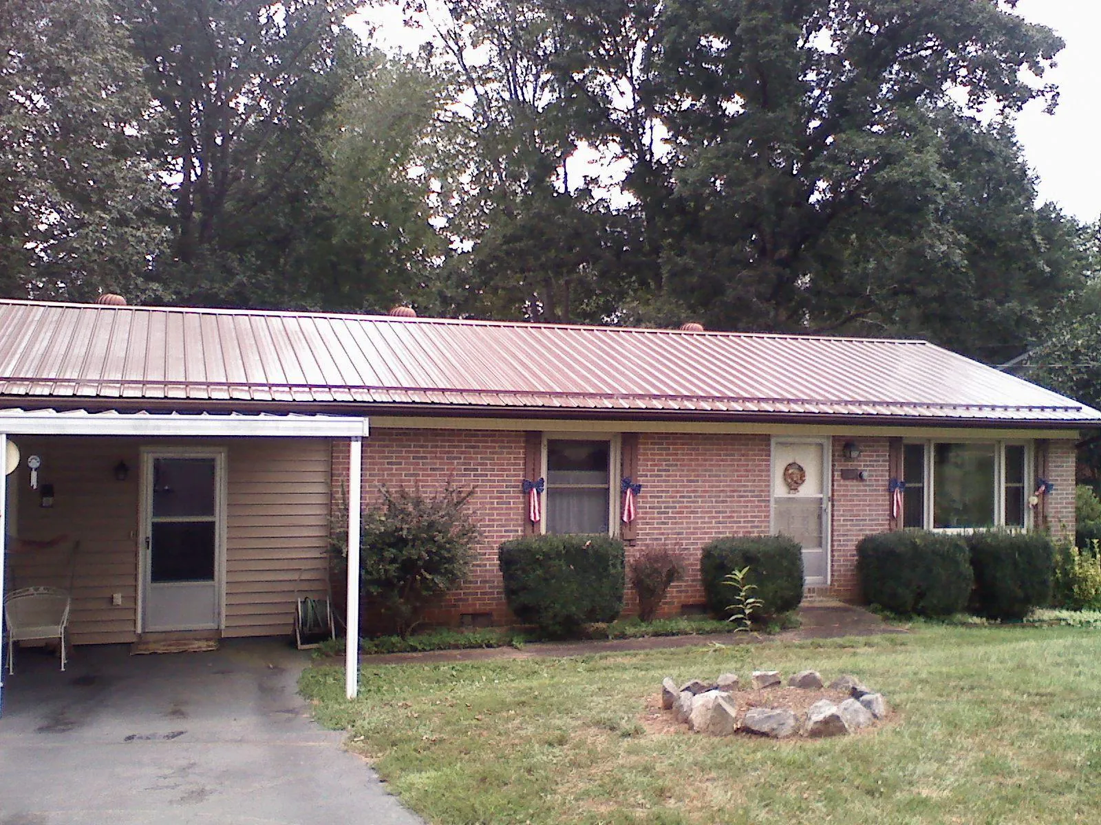 Bronze metal roof and carport on a brick ranch home — Roof Repair work by our crew in White Hall